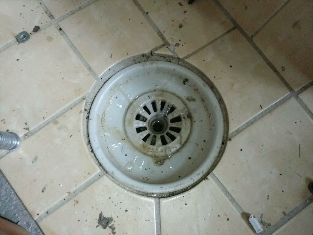 A shower drain on a job site before cleaning