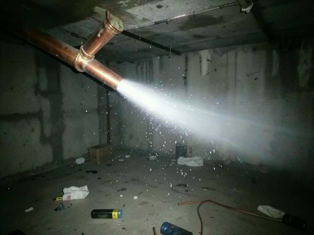 Burst pipe spraying water in a dark room